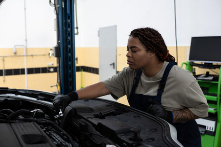Young African American woman demonstrates skill and passion while fixing a car in a garage.