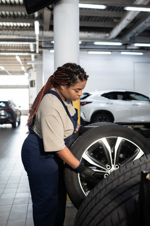 Young African American woman diligently repairs a vehicle in a vibrant auto garage