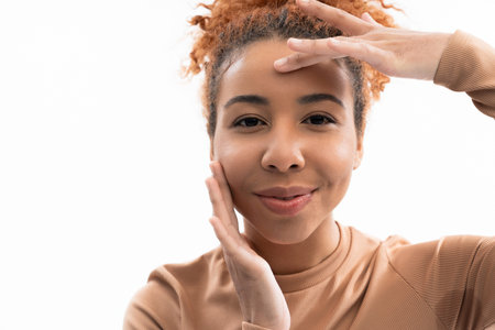 A young woman showcases her radiant smile and natural beauty against a simple backdrop.の写真素材