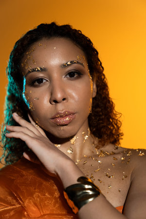 Young woman shines brightly with golden details, exuding charm in a warm, colorful setting.
