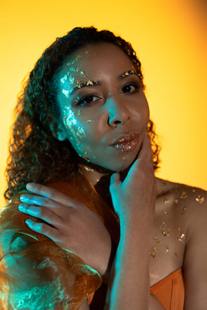 A stunning young woman showcases her unique style with golden details while posing beautifully.の写真素材