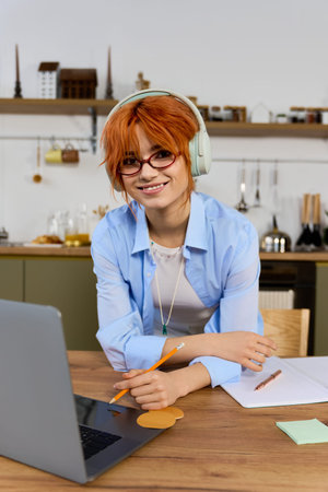 Beautiful red haired woman enjoys her day working in a cheerful home workspace with focus.