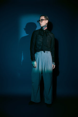 Stylish young man stands confidently against a dark backdrop, radiating charm.