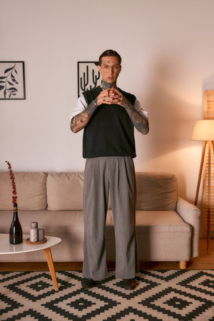 Young man in fashionable attire stands confidently in a modern living room with elegant decor