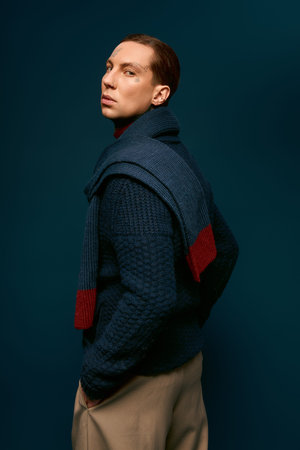 A young man stands gracefully, dressed in fashionable layers while exuding charm and style.