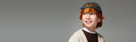 Redhead boy smiles happily while showcasing his stylish casual outfit in a studio setting, banner