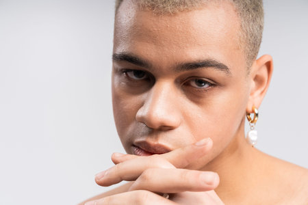 Handsome individual exudes confidence with a bold look and a contemplative gaze in soft lighting.