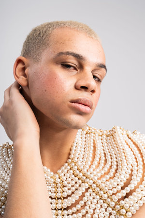 Handsome individual demonstrates fashion flair with unique pearl accessories and a confident pose.