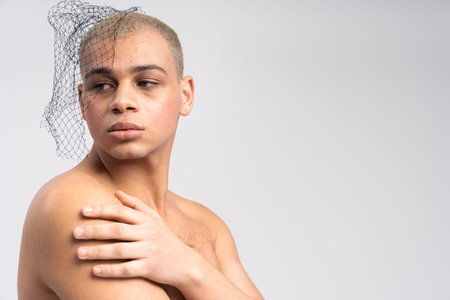 Handsome man showcases a striking look with a dramatic headpiece, embodying modern fashion art.