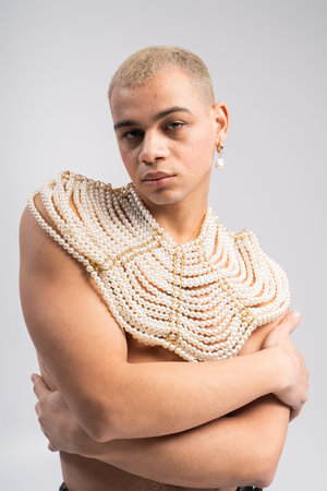 Handsome man poses confidently in a creative studio, wearing stunning pearl accessories.