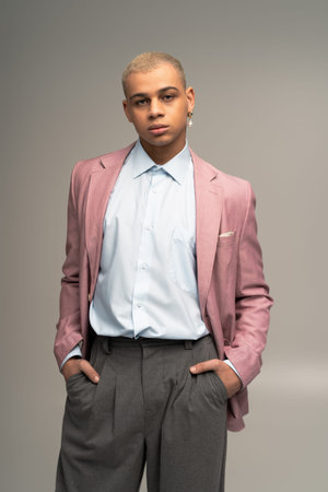 A stylish young man in a tailored pink blazer embodies elegance with his striking features.