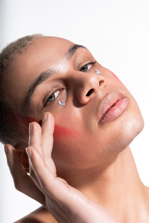 A handsome man poses elegantly, revealing his unique style with striking makeup and artistic flair