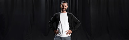 A charming man stands confidently, preparing for his theater performance under dramatic lighting.の写真素材