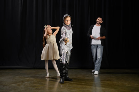 A male tutor showcases creative teaching as young performers engage in a lively theater exercise.