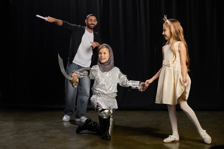 Stylish male educator engages kids in theater fun, showcasing creativity and teamwork in actions.の写真素材