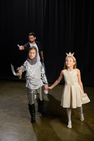 Male tutor leads fun theater session, inspiring kids to embrace their roles and creativity.