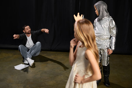 A male instructor passionately teaches theater skills to eager children, promoting fun learning.