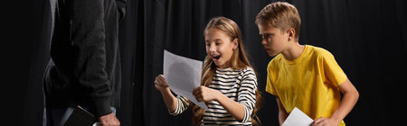 Excited kids eagerly learn theater skills from a stylish male tutor during a lively class.の写真素材