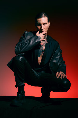 A stylish young man poses confidently against a vibrant backdrop, showcasing unique fashion.