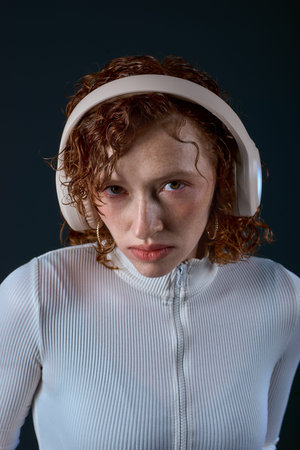 Young woman with red curls listens to music in a calm studio, lost in her melodies.