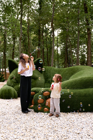 A young mother and her daughter make magical memories playing with bubbles in a park.
