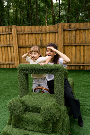 Young mother and her cheerful daughter enjoy playful moments in a vibrant park setting.の写真素材