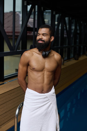 A shirtless Black man with a beard relaxes calmly in a spa center.