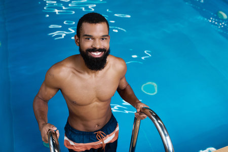 A shirtless man enjoys a moment of relaxation while smiling at the spa center pool.の写真素材