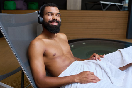 A shirtless man with a beard unwinds at a wellness center, immersed in relaxation and joy.の写真素材