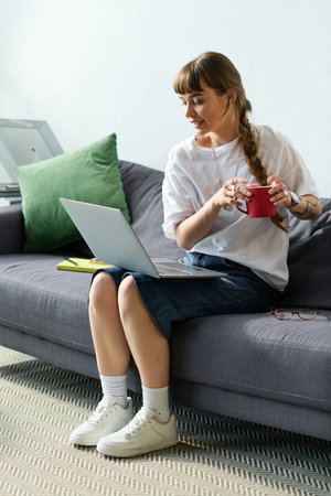 A young woman with bangs relaxes in her stylish apartment, sipping coffee and smiling.