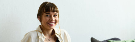 Young woman with bangs radiates joy while relaxing at home in her modern apartment space, banner