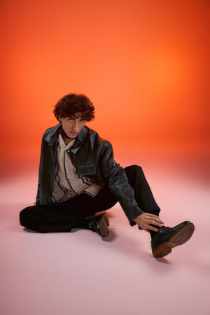 Stylish man sits on the floor, showcasing his confidence and unique fashion sense.