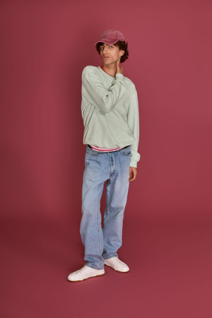 Handsome young man showcases relaxed fashion with a playful pose in a colorful setting.