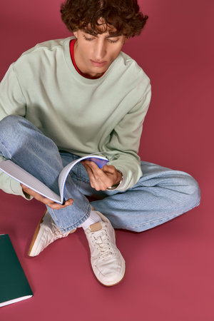 Handsome man dressed in casual fashion examines a notebook with a thoughtful expression on his face.