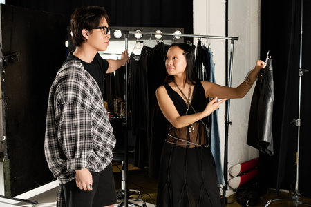 Model and designer collaborate backstage, selecting outfits and sharing ideas.