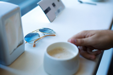 Photo sunglasses and a man's hand with cups of coffeeの写真素材