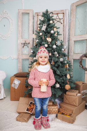 Beauty little girl with candles around the Christmas tree and many giftsの写真素材