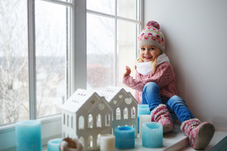 Little girl sitting on a window sillの写真素材