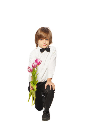Boy kneeling with tulips in a hand on a white backgroundの写真素材
