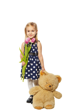 Little girl with flowers and a teddy bear on a white backgroundの写真素材