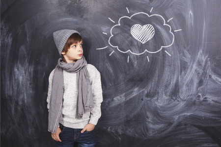 A boy on a gray background looking at the heartの写真素材