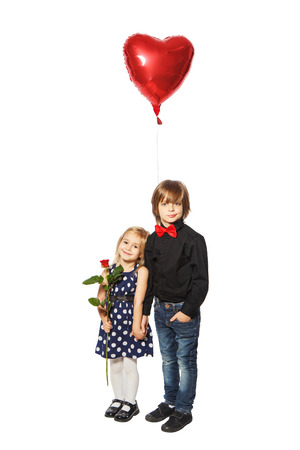 Girl with a rose in her hand standing near the boy with balloon in the form of heart on a white backgroundの写真素材