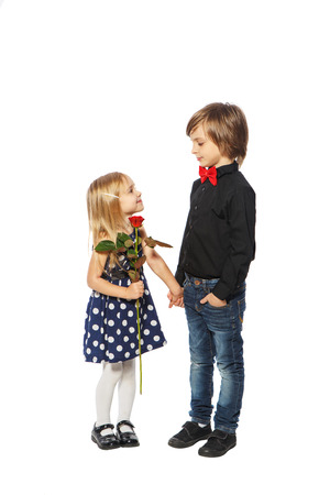 Girl with a rose in her hand standing near the boy on a white backgroundの写真素材