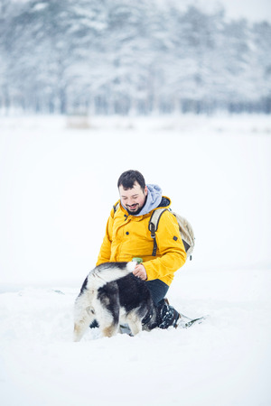 Man and dog in the snow in a forest in the afternoonの写真素材