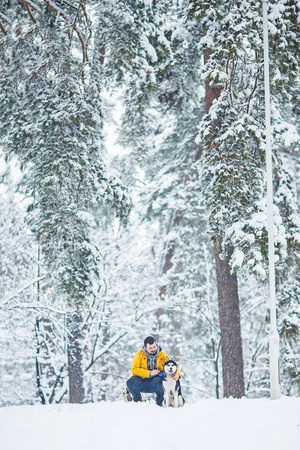 Man and dog in the snow in a forest in the afternoonの写真素材