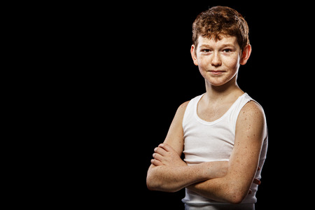 Red-haired boy in a white T-shirt on a black backgroundの写真素材