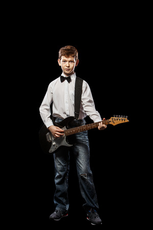 The red-haired boy in a white shirt with an electric guitar on a black backgroundの写真素材