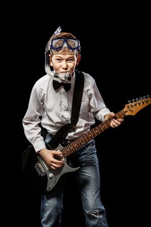The red-haired boy in a white shirt with an electric guitar on a black backgroundの写真素材