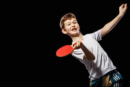 Boy playing table tennis on a black backgroundの写真素材