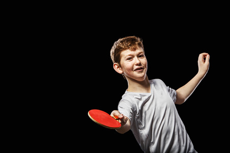 Boy playing table tennis on a black backgroundの写真素材